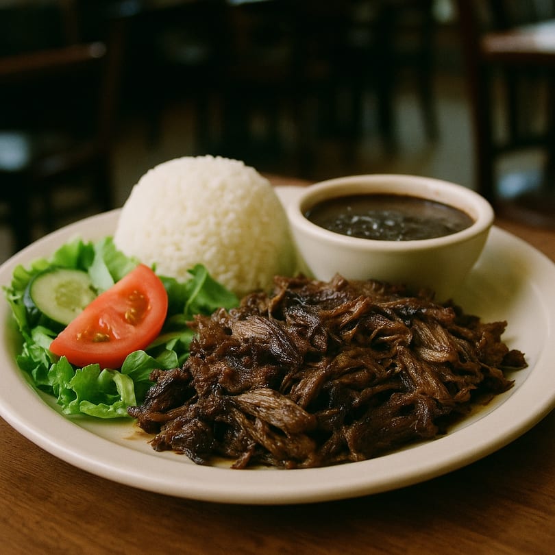 Cuban shredded beef with white rice, black beans, and a side salad on a white plate.